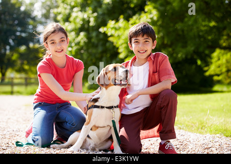 Hispanic Children Taking Dog For Walk In Countryside Stock Photo