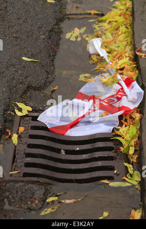 England football team flag going down the drain. England football team flag in the gutter among leaves and debris. Stock Photo