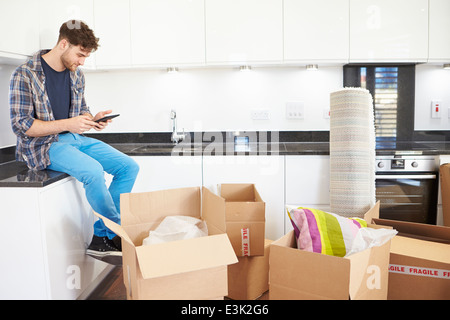 Man Sending Text Message Having Moved Into New Home Stock Photo