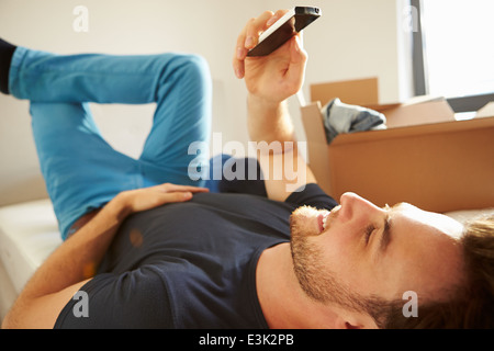 Man Sending Text Message Having Moved Into New Home Stock Photo