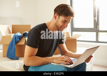 Man Moving Into New Home Using Laptop Computer Stock Photo