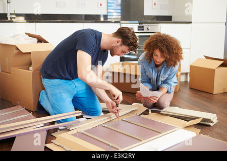 Couple Putting Together Self Assembly Furniture In New Home Stock Photo