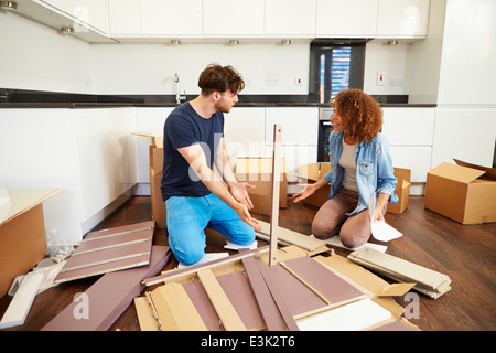 Couple Putting Together Self Assembly Furniture In New Home Stock Photo