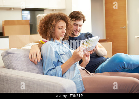 Couple Sitting On Sofa Looking At Paint Charts Stock Photo