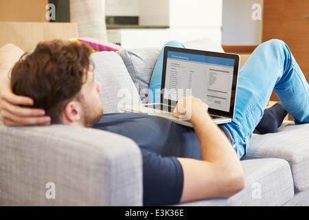 Man Using Online Banking Relaxing On Sofa Stock Photo