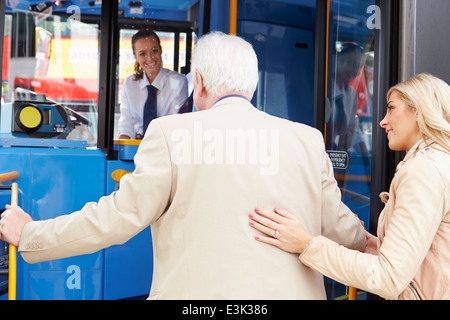 Woman Helping Senior Man To Board Bus Stock Photo