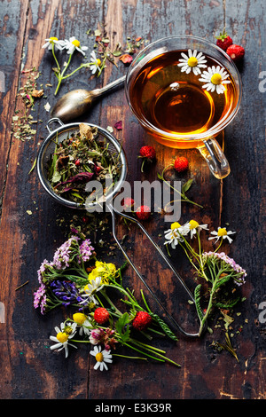 Herbal tea with honey, wild berry and flowers on wooden background