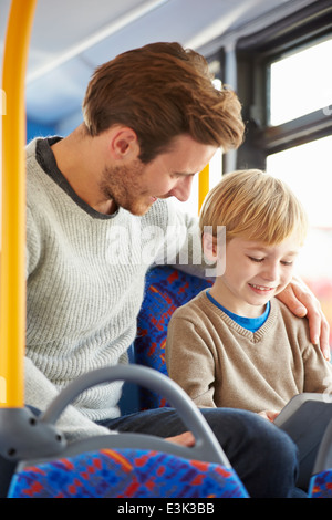 Son Using Digital Tablet On Bus Journey With Father Stock Photo