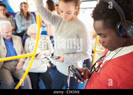 Passengers Using Mobile Devices On Bus Journey Stock Photo