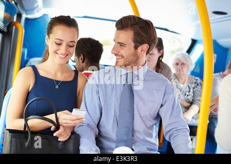 Businessman And Woman Looking At Mobile Phone On Bus Stock Photo