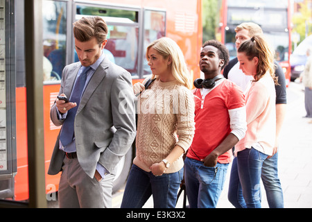 Queue Of People Waiting At Bus Stop Stock Photo