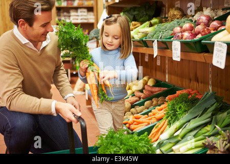 Father And Daughter Choosing Fresh Vegetables In Farm Shop Stock Photo