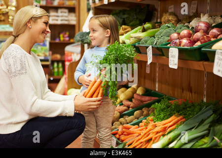 Mother And Daughter Choosing Fresh Vegetables In Farm Shop Stock Photo