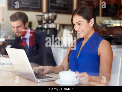 Businesswoman Using Laptop In Coffee Shop Stock Photo
