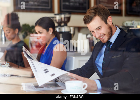 Businessman Reading Newspaper In Coffee Shop Stock Photo