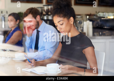 Businesswoman Writing Notes In Coffee Shop Stock Photo
