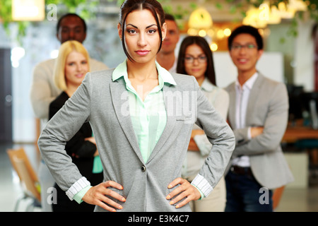 Serious beautiful businesswoman standing in front her colleagues Stock Photo