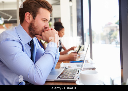 Businessman Using Laptop In Coffee Shop Stock Photo