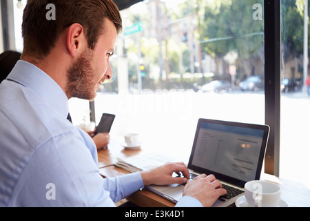 Businessman Using Laptop In Coffee Shop Stock Photo