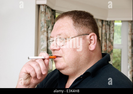 Man holding & smoking an electronic disposable E Cigarette (e-cigarette) Stock Photo