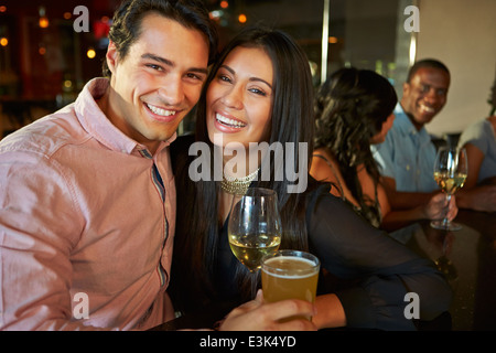 Couple Enjoying Drink At Bar With Friends Stock Photo