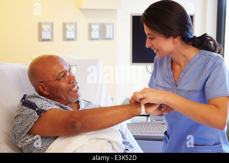 Nurse Putting Wristband On Senior Male Patient In Hospital Stock Photo