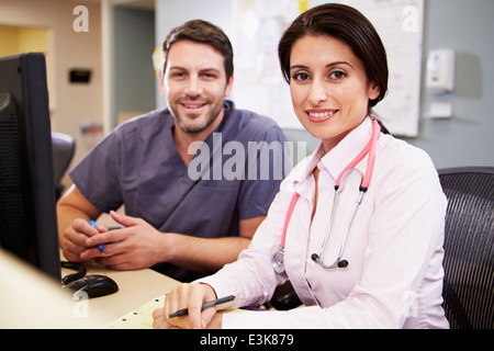 Female Doctor With Male Nurse Working At Nurses Station Stock Photo