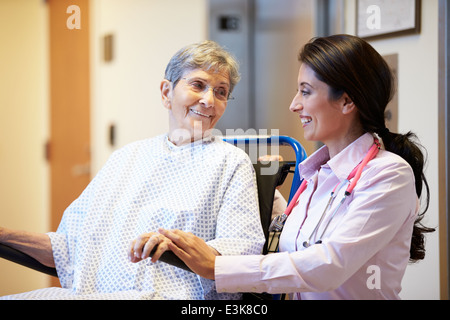 Senior Female Patient Being Pushed In Wheelchair By Doctor Stock Photo