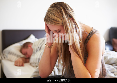 Worried Teenage Girl In Bedroom With Boyfriend Stock Photo