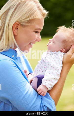 Loving Mother Holding Baby Daughter In Garden Stock Photo