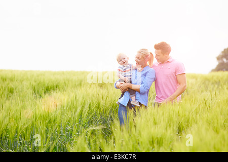 Family Walking In Field Carrying Young Baby Son Stock Photo