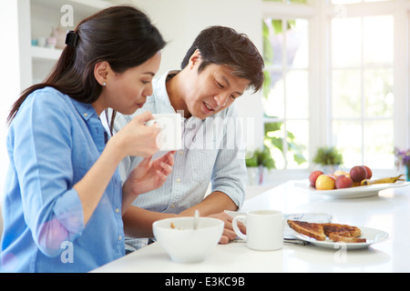 Asian Couple Reading Newspaper At Breakfast Stock Photo