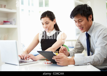 Asian Couple Using Digital Devices At Breakfast Table Stock Photo