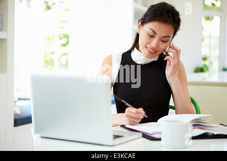 Asian Businesswoman Working From Home Using Mobile Phone Stock Photo