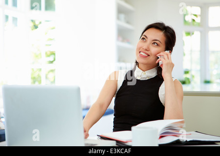Asian Businesswoman Working From Home Using Mobile Phone Stock Photo