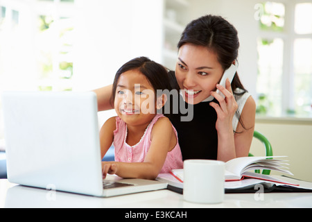 Busy Mother Working From Home With Daughter Stock Photo