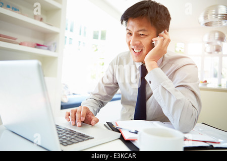 Asian Businessman Working From Home Using Mobile Phone Stock Photo