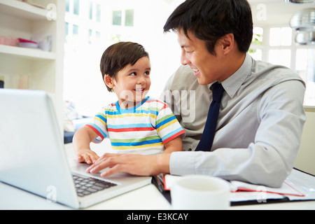 Busy Father Working From Home With Son Stock Photo