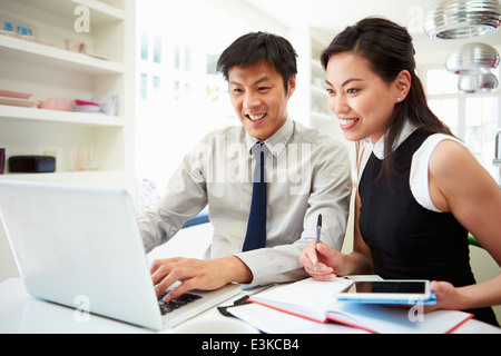 Asian Couple Working From Home Looking At Personal Finances Stock Photo