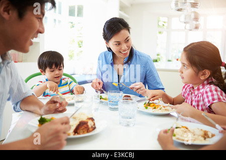 Asian Family Sitting At Table Eating Meal Together Stock Photo