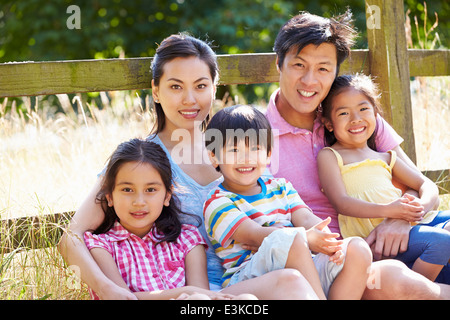Asian Family Relaxing By Gate On Walk In Countryside Stock Photo