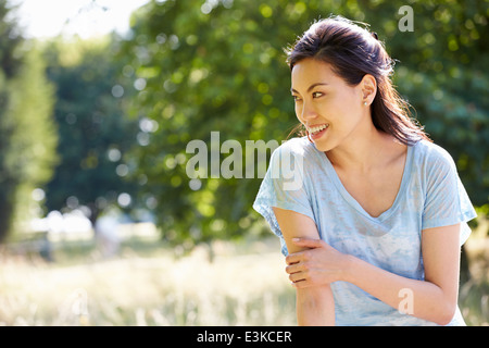Pretty Asian Woman Sitting On Fence In Countryside Stock Photo