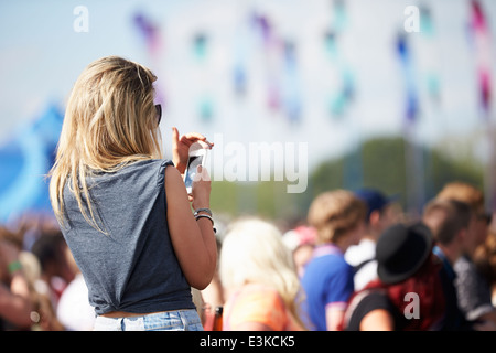 Young Woman At Outdoor Music Festival Using Mobile Phone Stock Photo