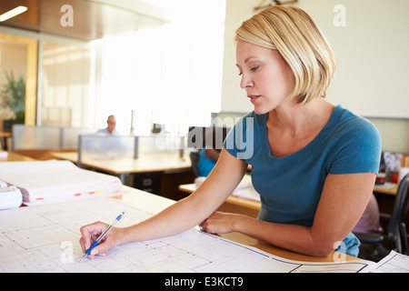 Female Architect Studying Plans In Office Stock Photo