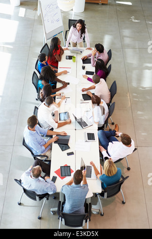 Businesswoman Addressing Meeting Around Boardroom Table Stock Photo