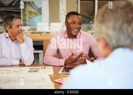 Group Of Architects Sitting Around Table Having Meeting Stock Photo