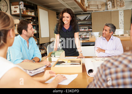 Female Boss Leading Meeting Of Architects Sitting At Table Stock Photo