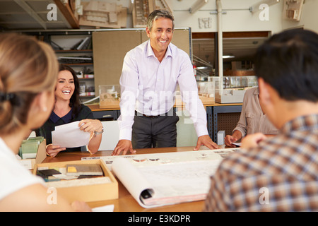 Male Boss Leading Meeting Of Architects Sitting At Table Stock Photo