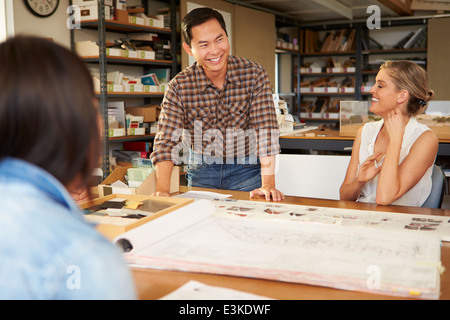 Three Architects Sitting Around Table Having Meeting Stock Photo