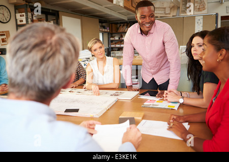 Male Boss Leading Meeting Of Architects Sitting At Table Stock Photo